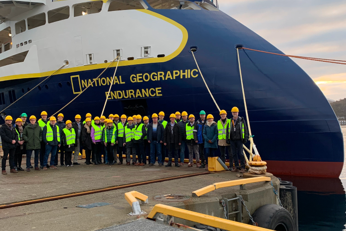 A picture of people in hard hats in front of the expedition cruise National Geographic Endurance